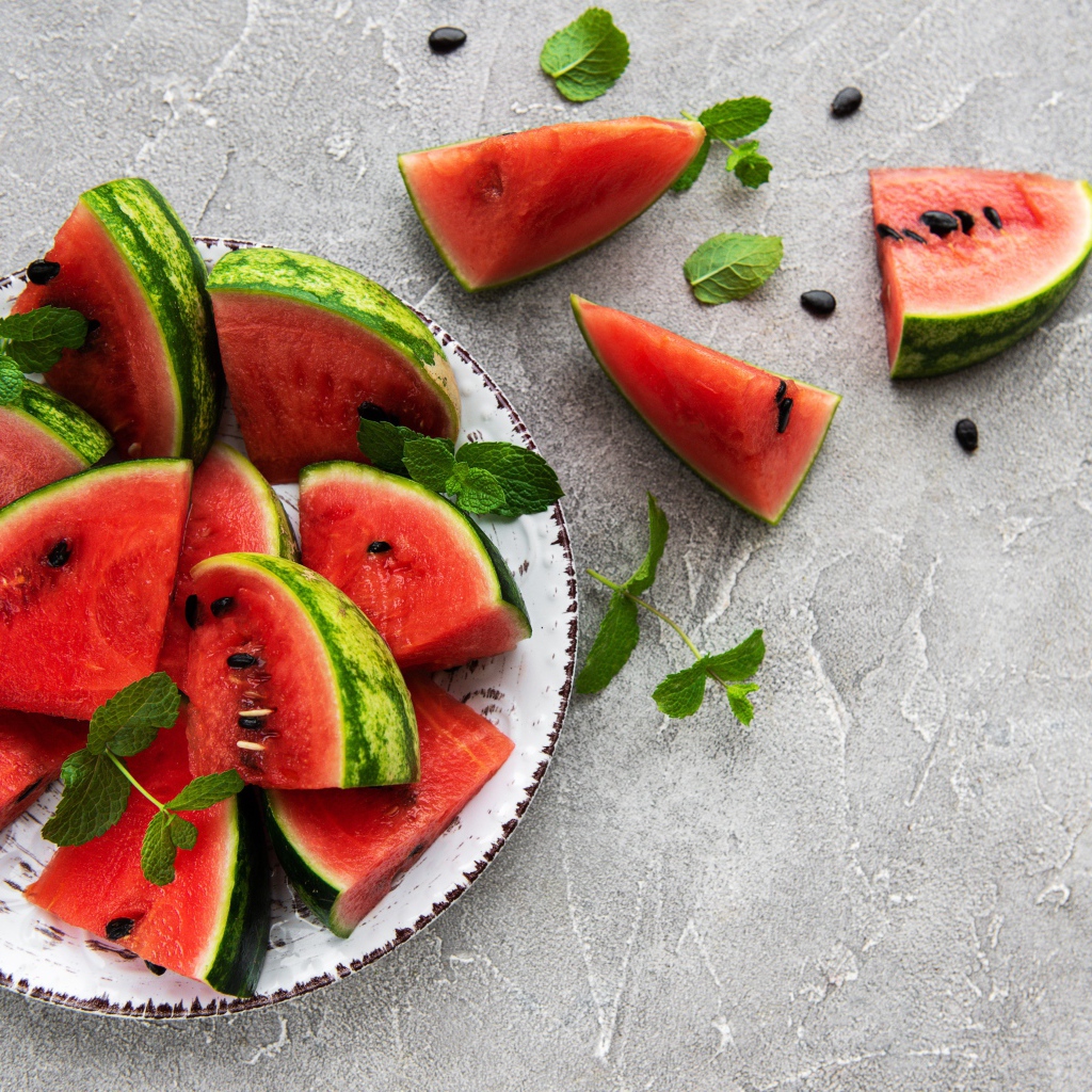 Полосатый арбуз нарезан кусочками на тарелке