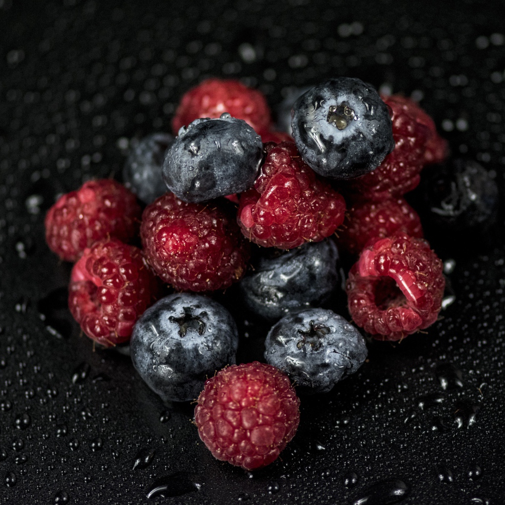 Мокрые ягоды черники и малины на черном фоне
