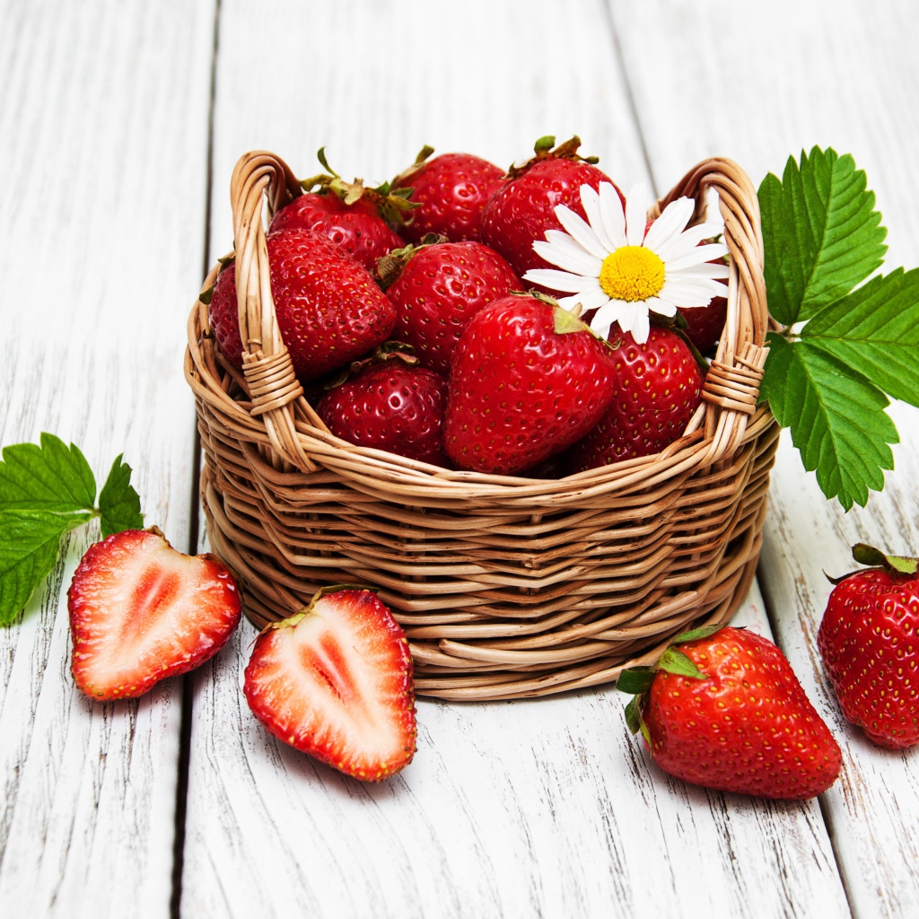 Плетеная корзинка с клубникой, ромашкой и зелеными листьями