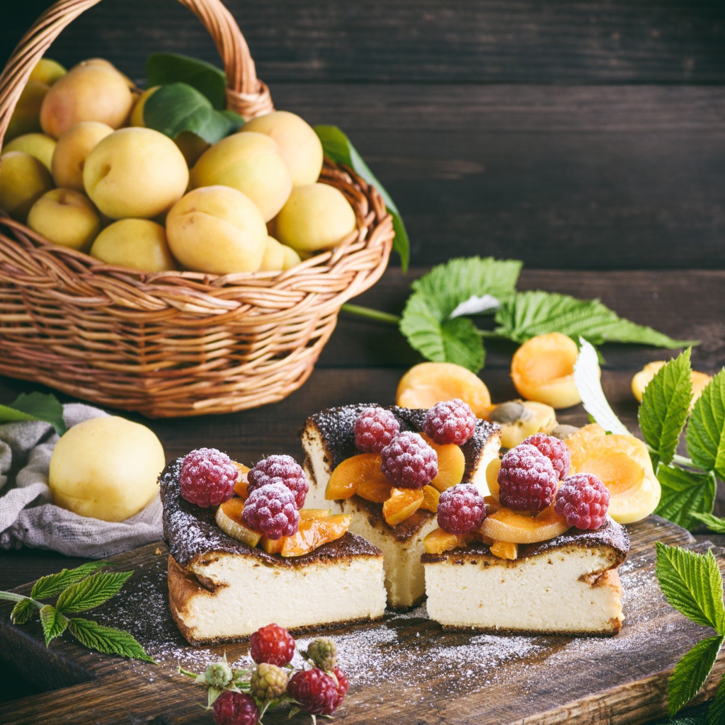 Вкусный фруктово - ягодный пирог на столе с корзиной с абрикосами