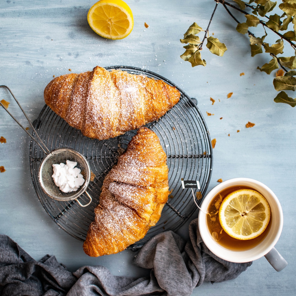 Два свежих круассана на столе с чаем