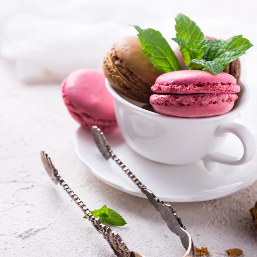 Разноцветный десерт макарун в белой чашке на столе