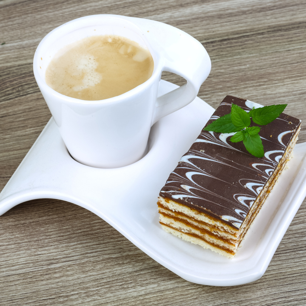 Чашка капучино на тарелке с пирожным 