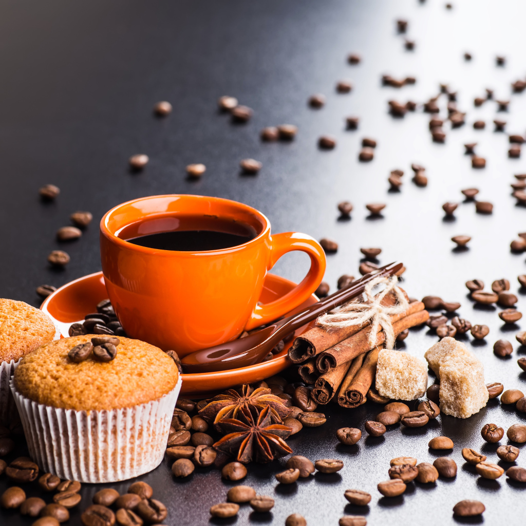 Чашка кофе на столе с кексами, кофейными зернами, корицей и бадьяном
