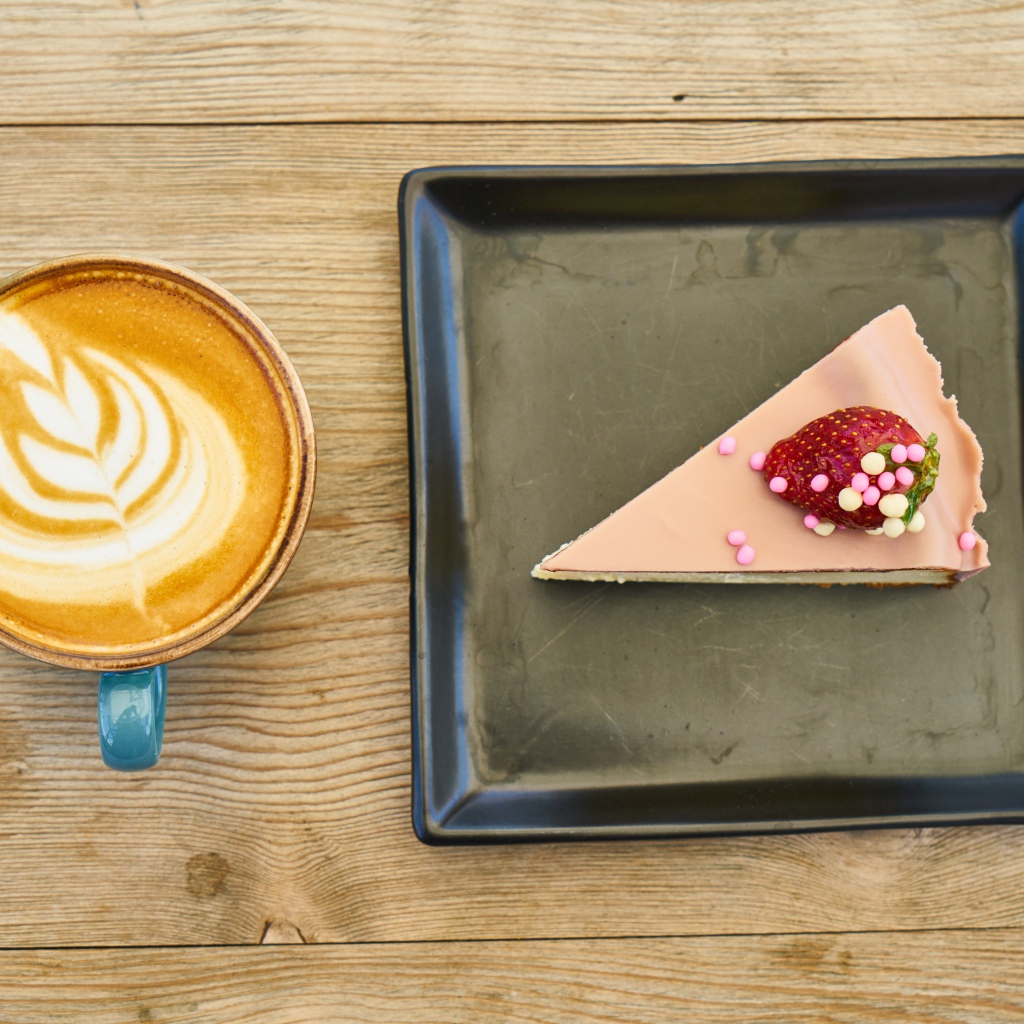 Кусок торта на черной тарелке с кофе