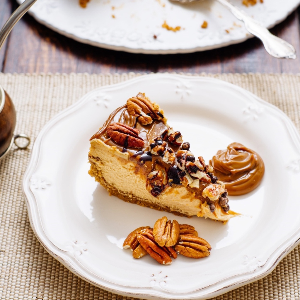 Кусок торта с орехами на белой тарелке на столе с кофе