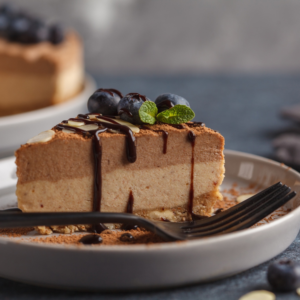 Кусок чизкейка с черникой и шоколадом на тарелке с вилкой