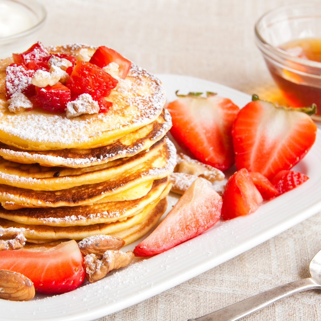 Appetizing sweet pancakes with icing sugar and strawberries