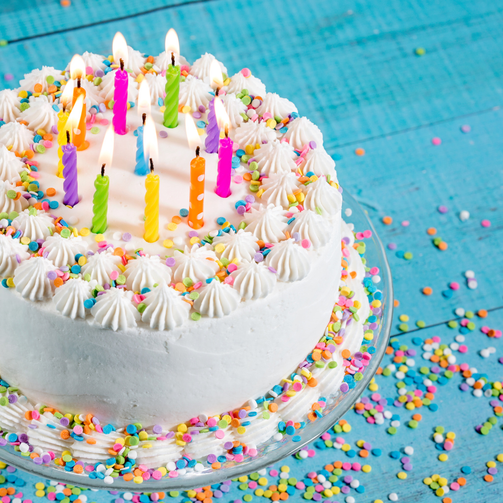 Большой праздничный торт с кремом и свечами на голубом столе