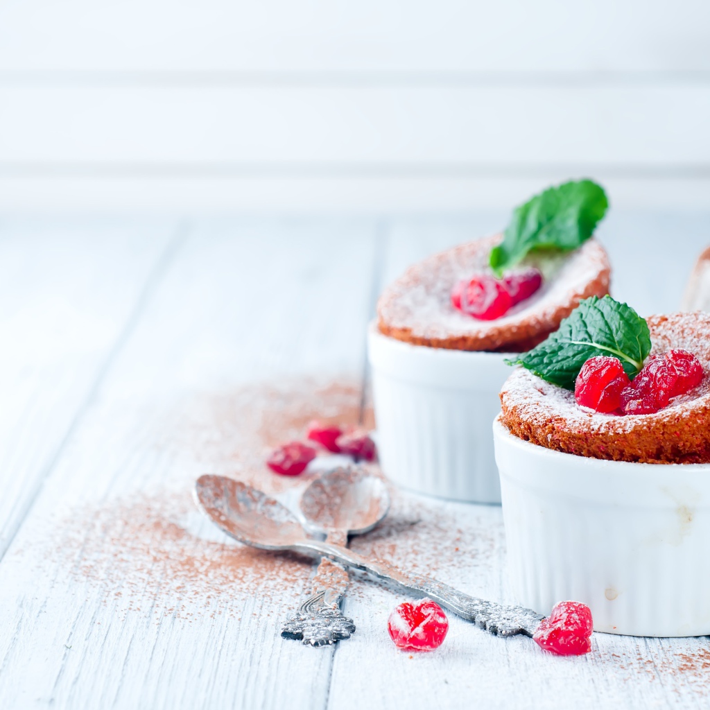 Пирожное с ягодами и сахарной пудрой на столе с ложками