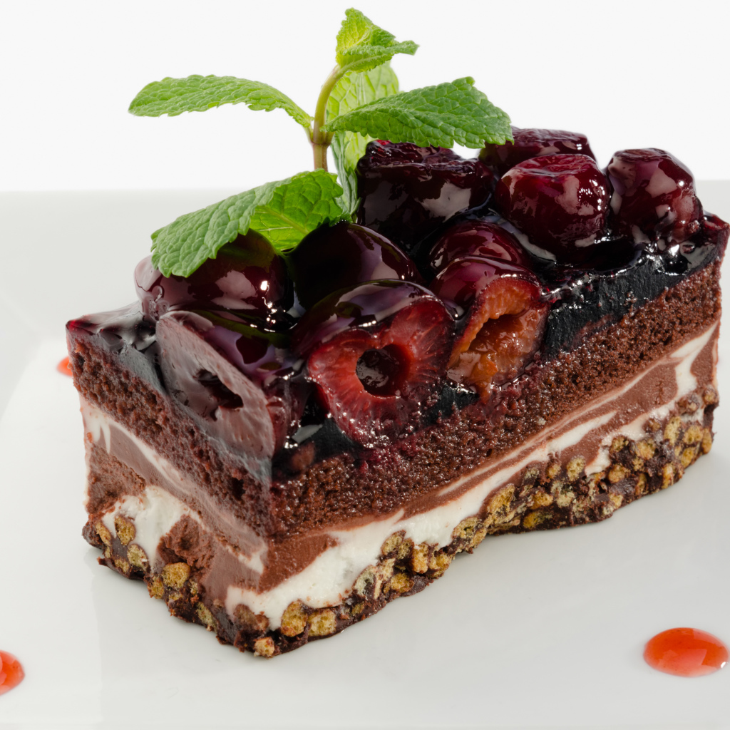 Пирожное с черешней и листиками мяты на сером фоне