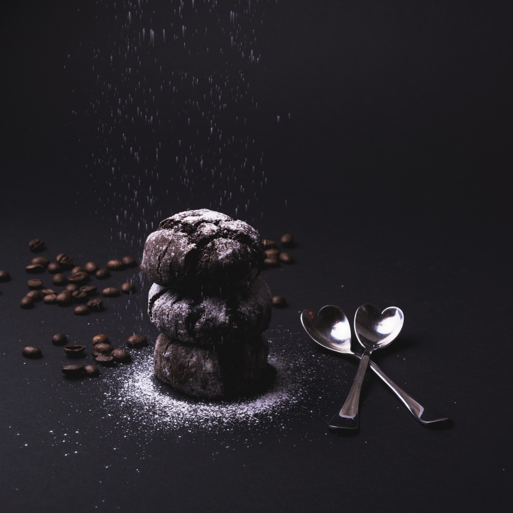 Шоколадное печенье с сахарной пудрой на черном фоне с кофейными зернами