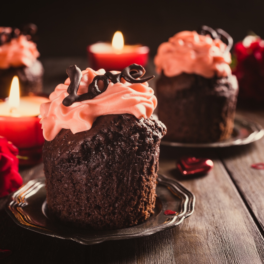 Шоколадные кексы с кремом на столе со свечами и розами