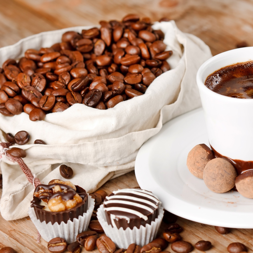 Шоколадные конфеты на столе с чашкой кофе и мешком с кофейными зернами