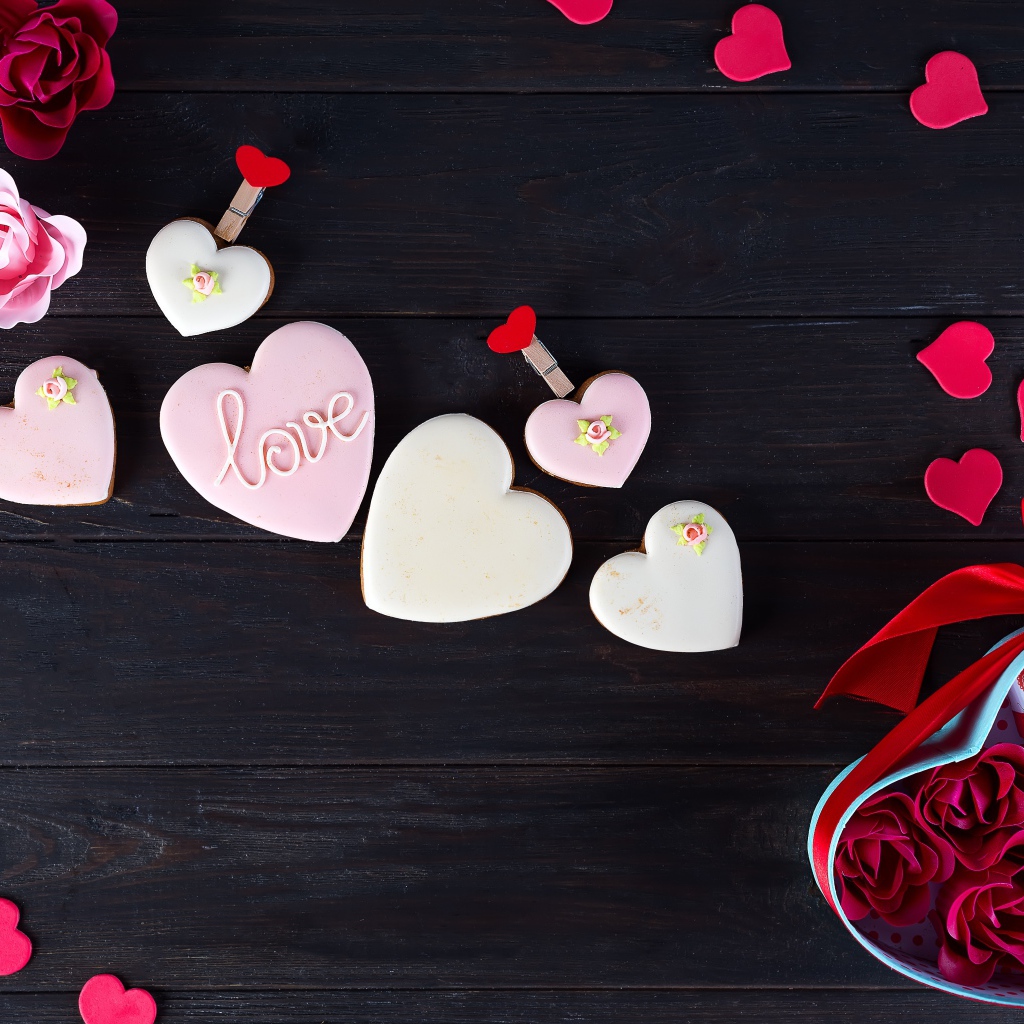 Печенье с глазурью на черной поверхности с сердечками и подарком