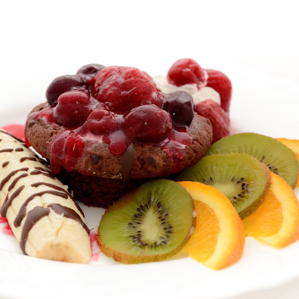 Печенье с вареньем, кусочками банана, киви и апельсина на белом фоне