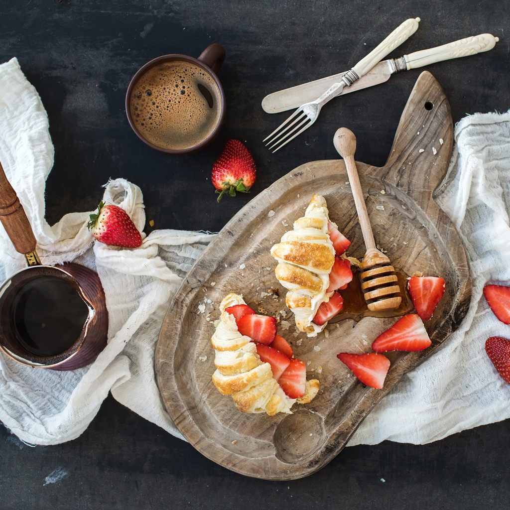 Круассаны на доске с клубникой и медом