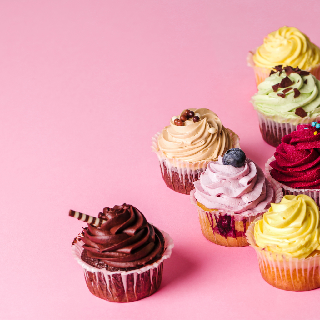 Кексы с разноцветным кремом на розовом фоне