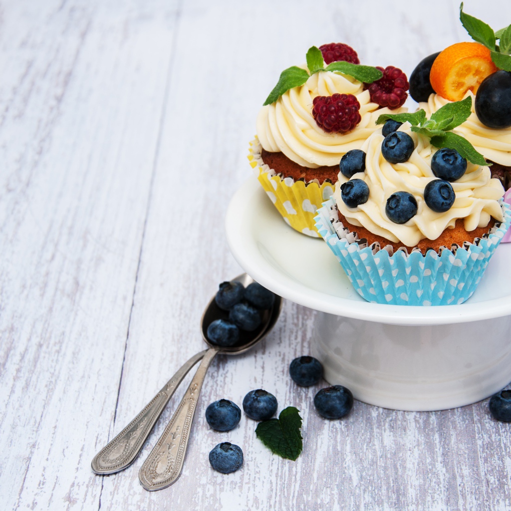 Cupcakes with cream on a white dish with berries