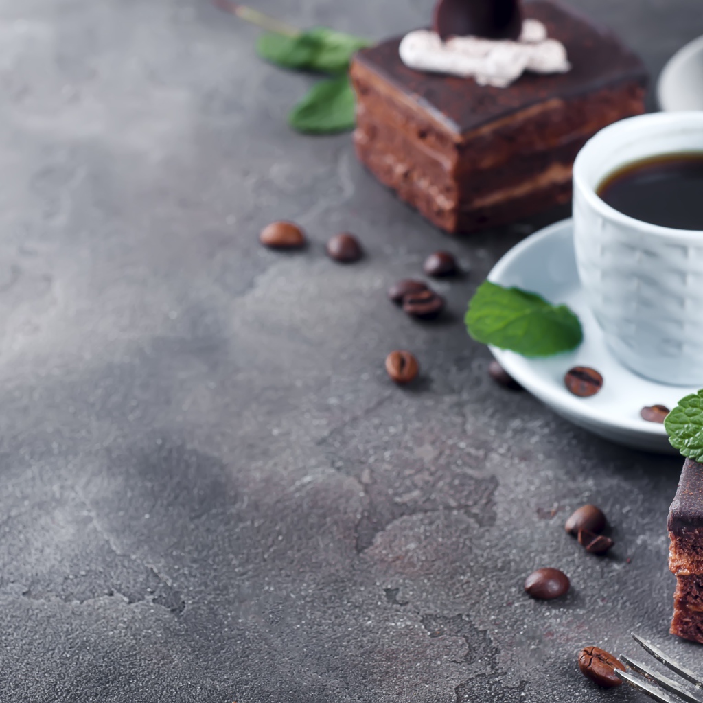 Аппетитное шоколадное пирожное на сером столе с чашкой кофе