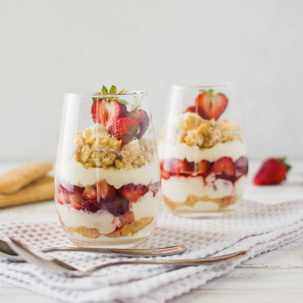 Десерт с клубникой в стеклянных стаканах на столе 