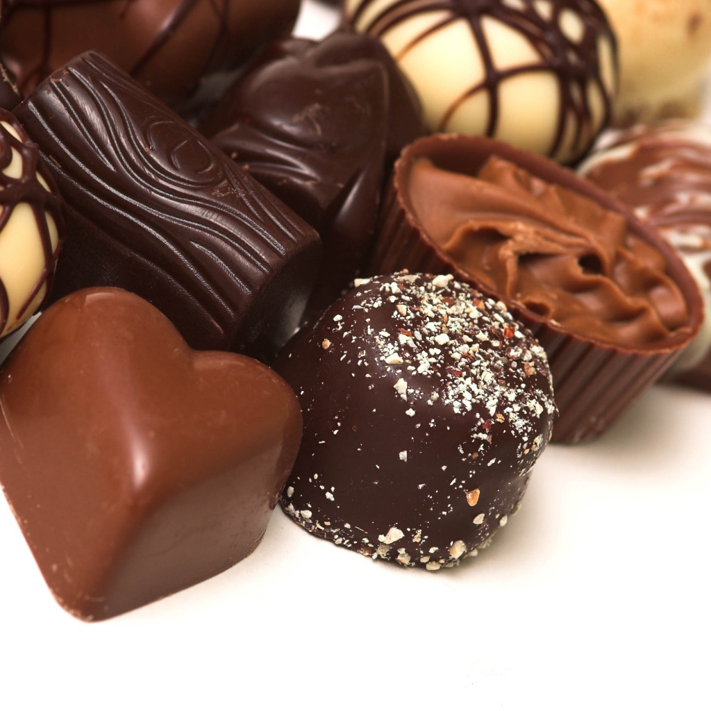 Разные шоколадные конфеты на белом фоне 