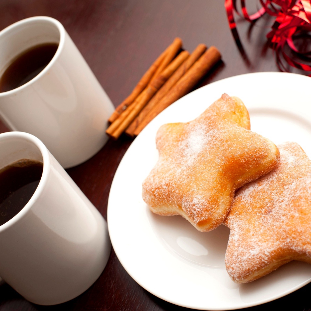 Пончики на столе с кофе и палочками корицы