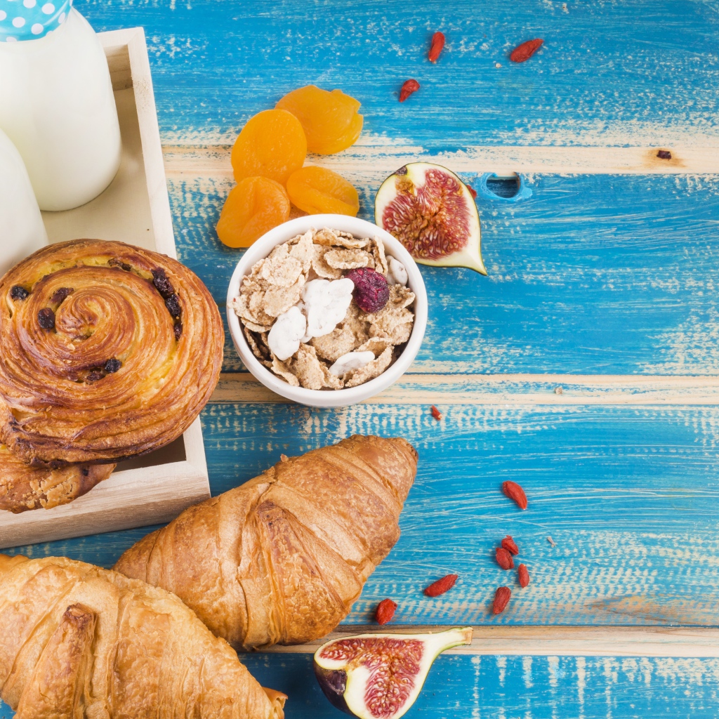 Свежая выпечка, молоко и мюсли на завтрак на столе