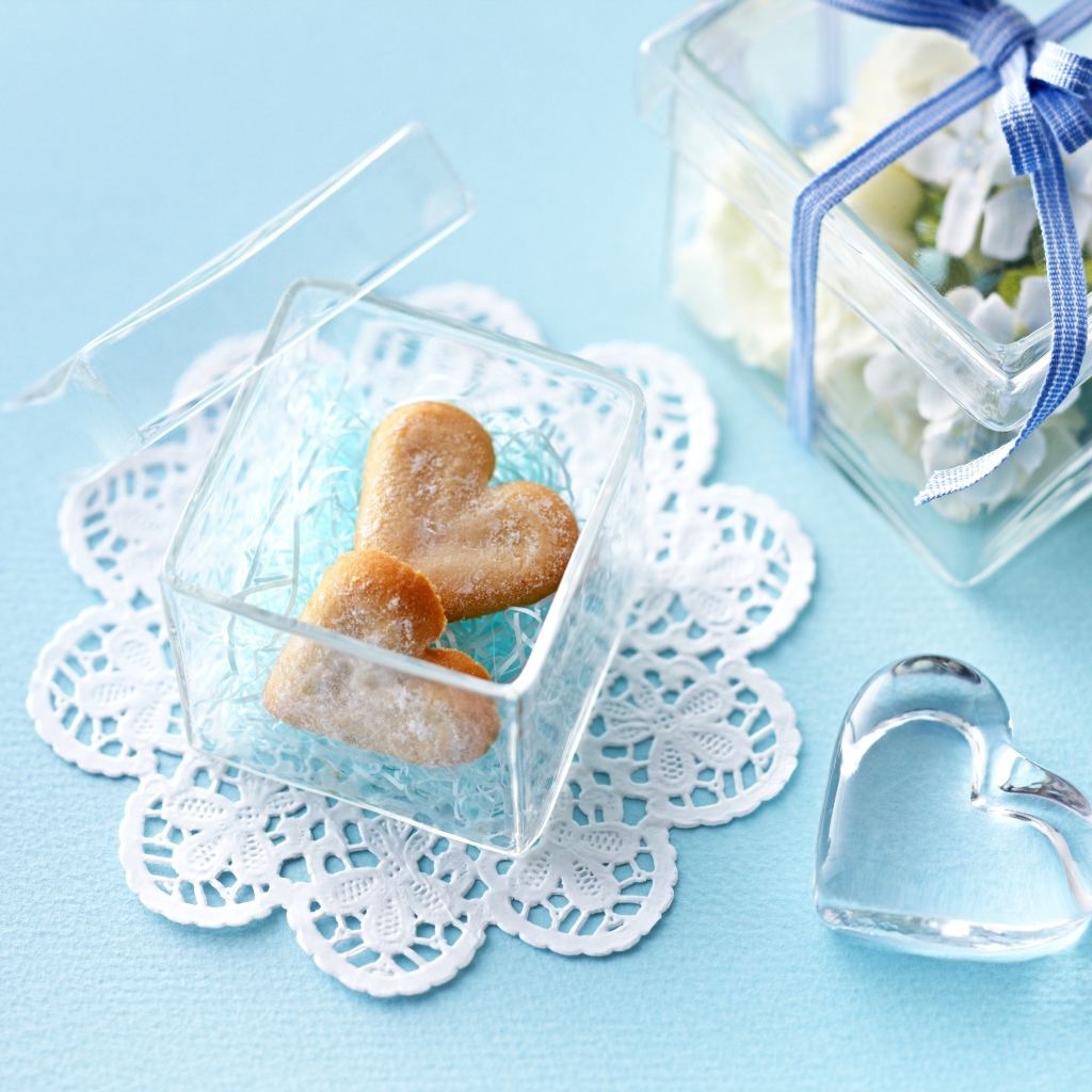 Песочное печенье в форме сердца в стеклянной шкатулке на голубом столе 