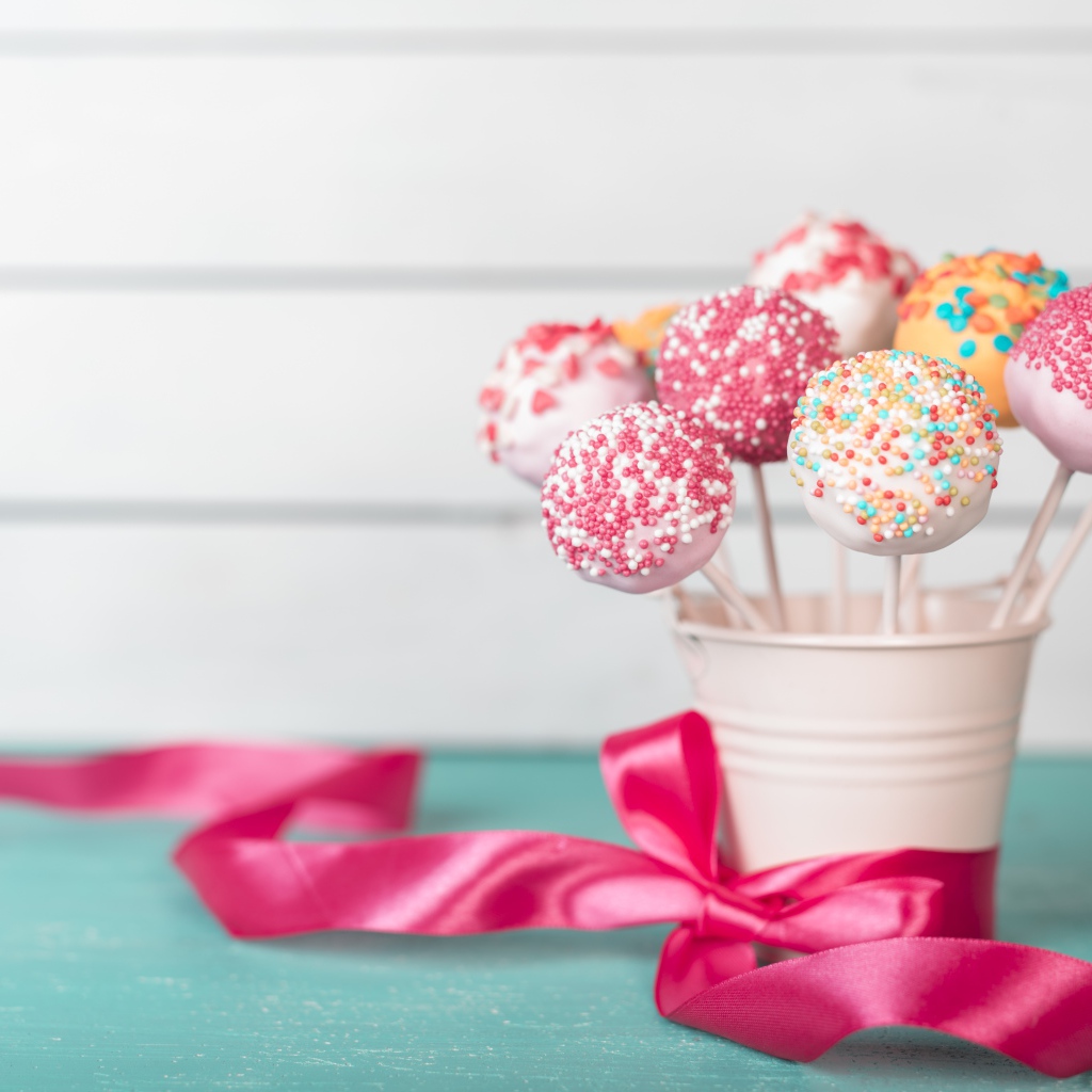 Леденцы в стакане на столе с розовым бантом из ленты