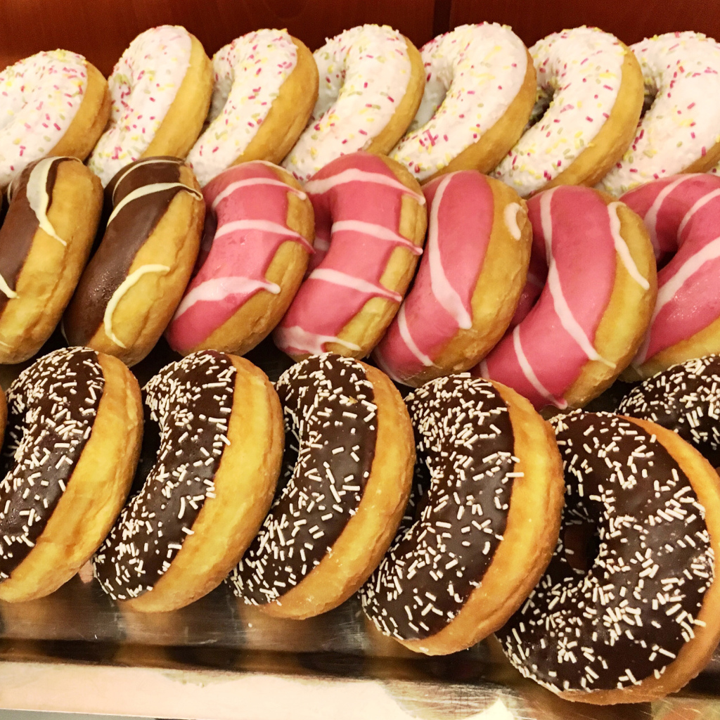 Много вкусных сладких пончиков с глазурью на столе 
