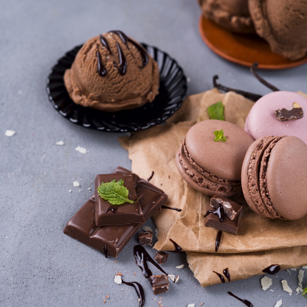 Печенье макарун на серой поверхности с мороженым и шоколадом