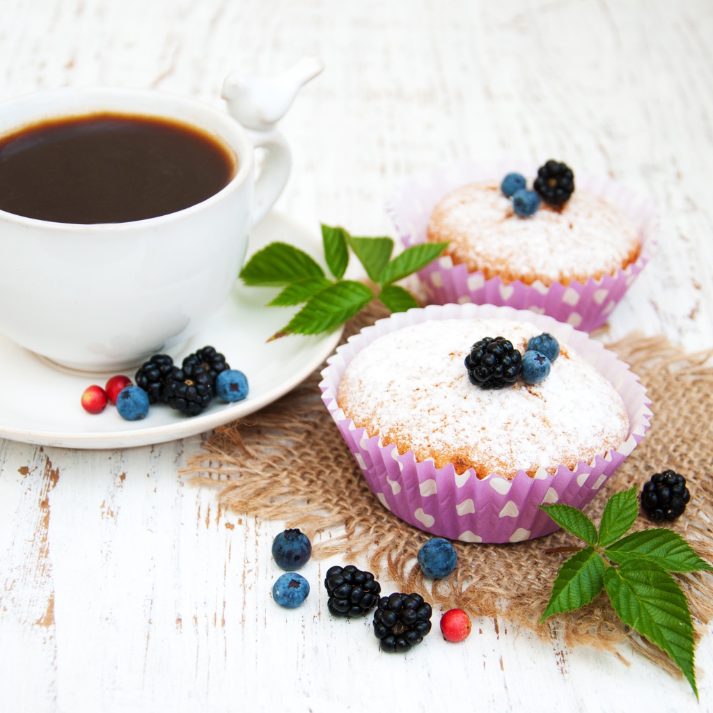 Кексы с сахарной пудрой и ягодами на столе с какао