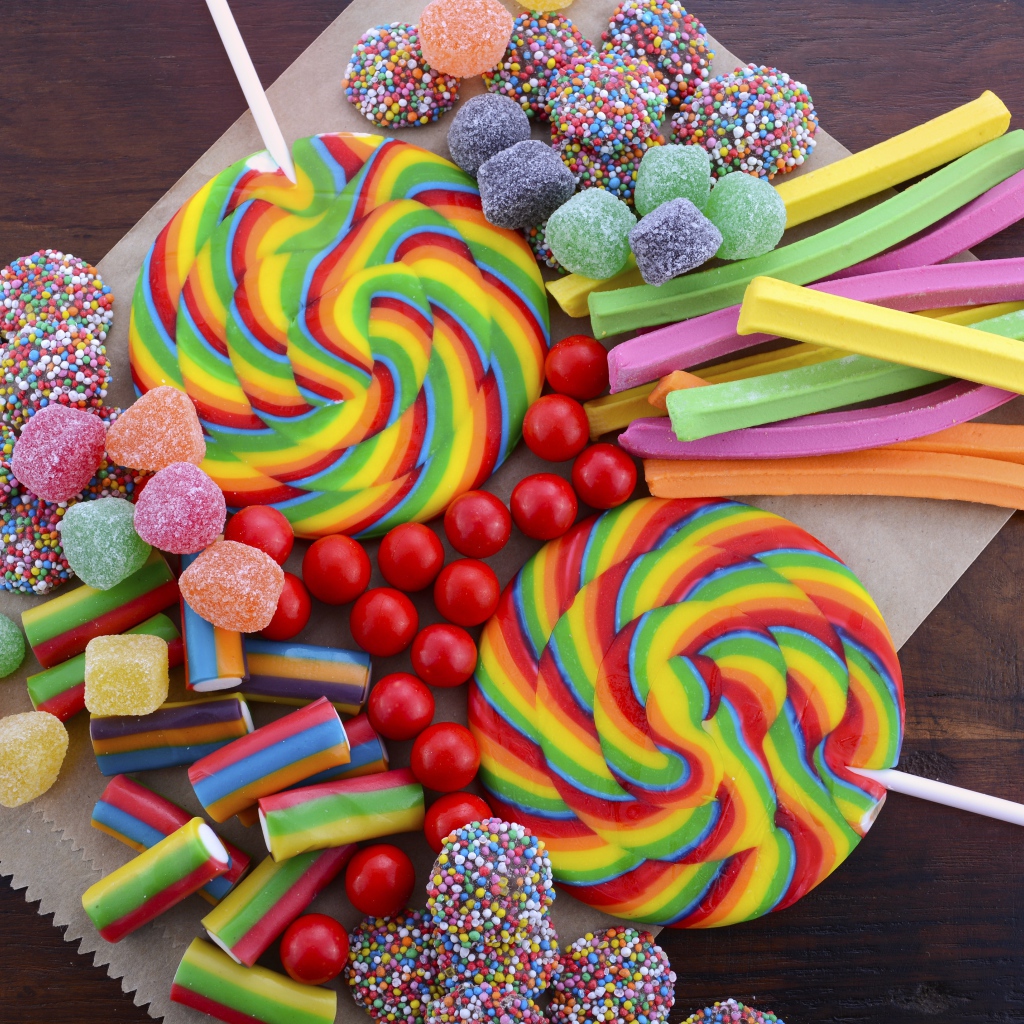 Разноцветные желейные конфеты, мармелад и леденцы на палочке на столе