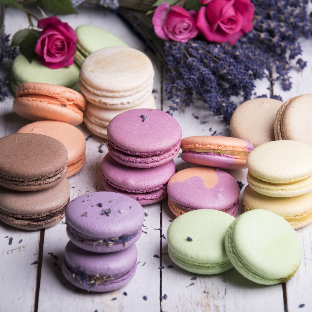 Разноцветный десерт макарон на столе с лавандой и розами