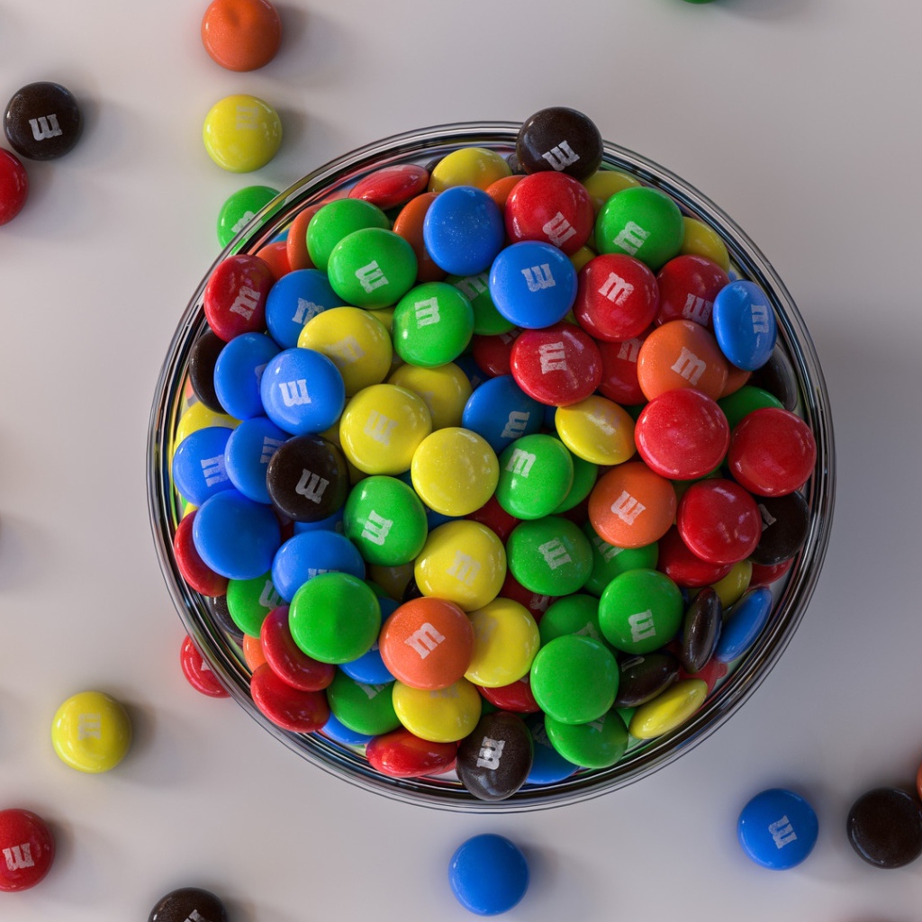 Разноцветные конфеты с миске на сером столе