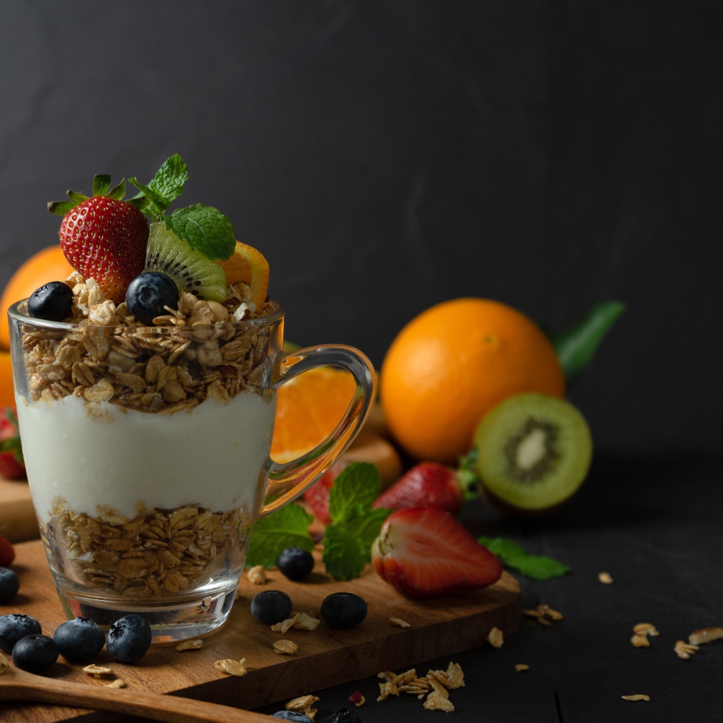 Овсяные хлопья с чашке с йогуртом на столе с ягодами и фруктами