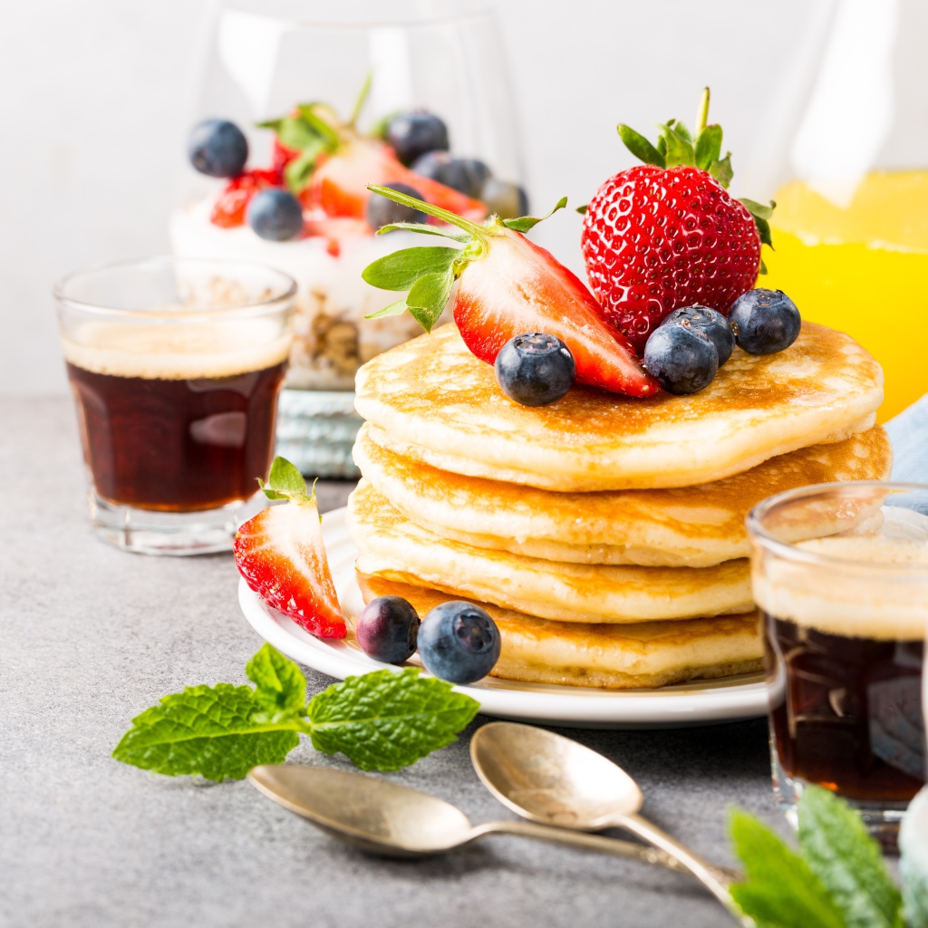 Оладьи с ягодами на столе с соком