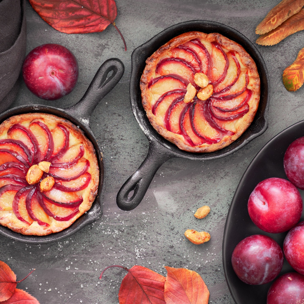 Пирог на столе с розовыми крупными сливами