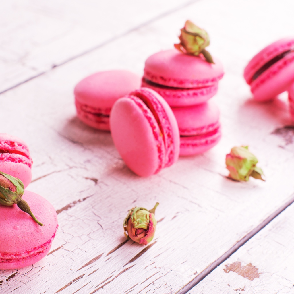 Розовый десерт макарон на столе с сухими розами