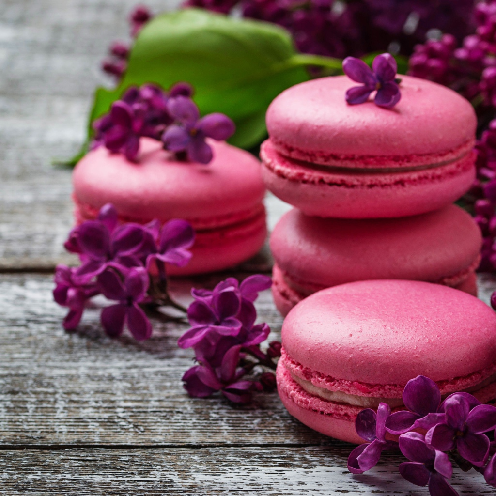 Розовый десерт макарон на столе с сиренью