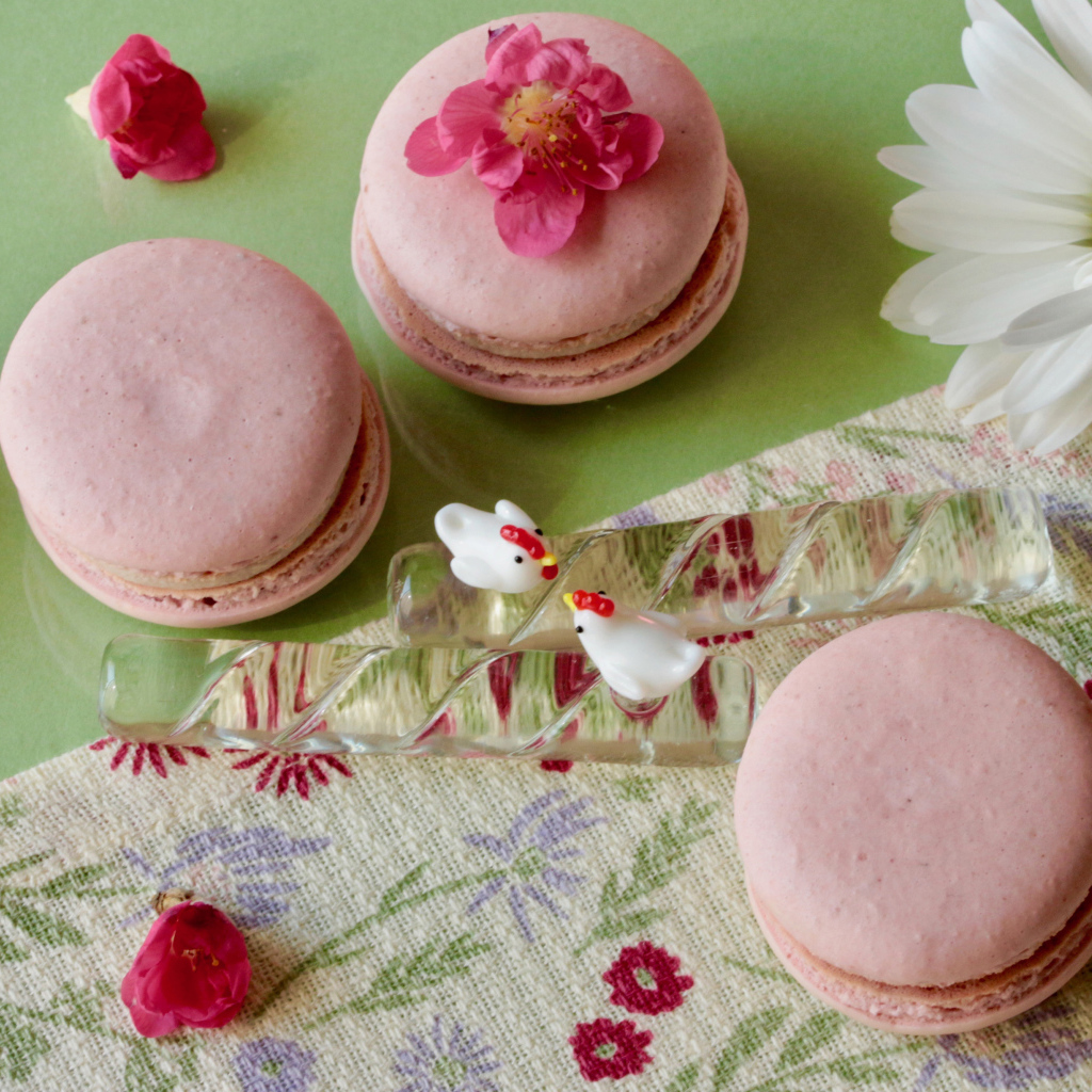 Розовый десерт макарон на столе с белыми цветами ромашек