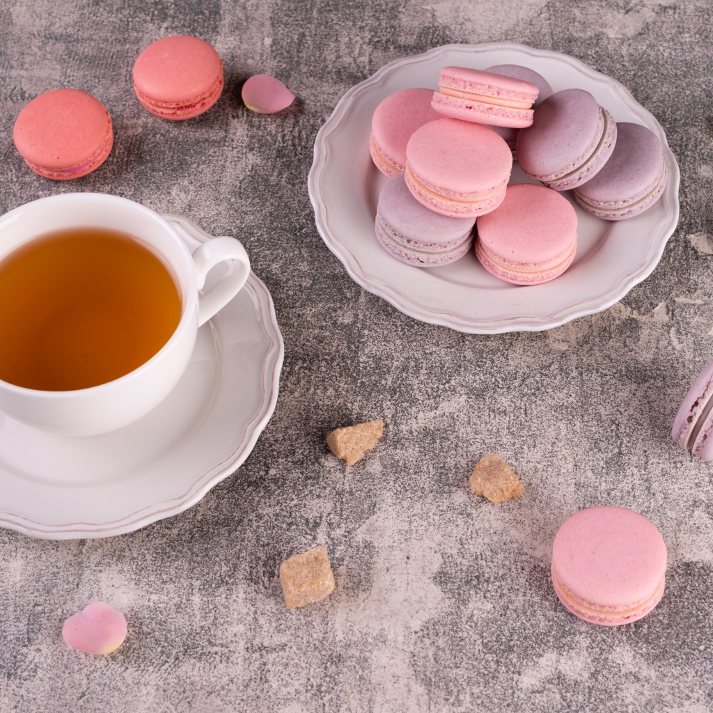 Тарелка с десертом макарун на столе с чашкой чая