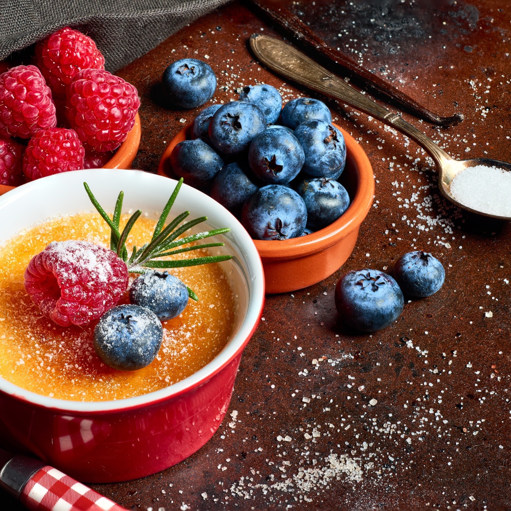 Пудинг на столе с ягодами малины и черники