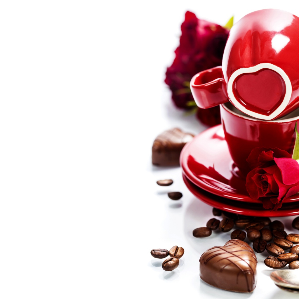 Красные чашки на белом фоне с шоколадными конфетами и кофейными зернами