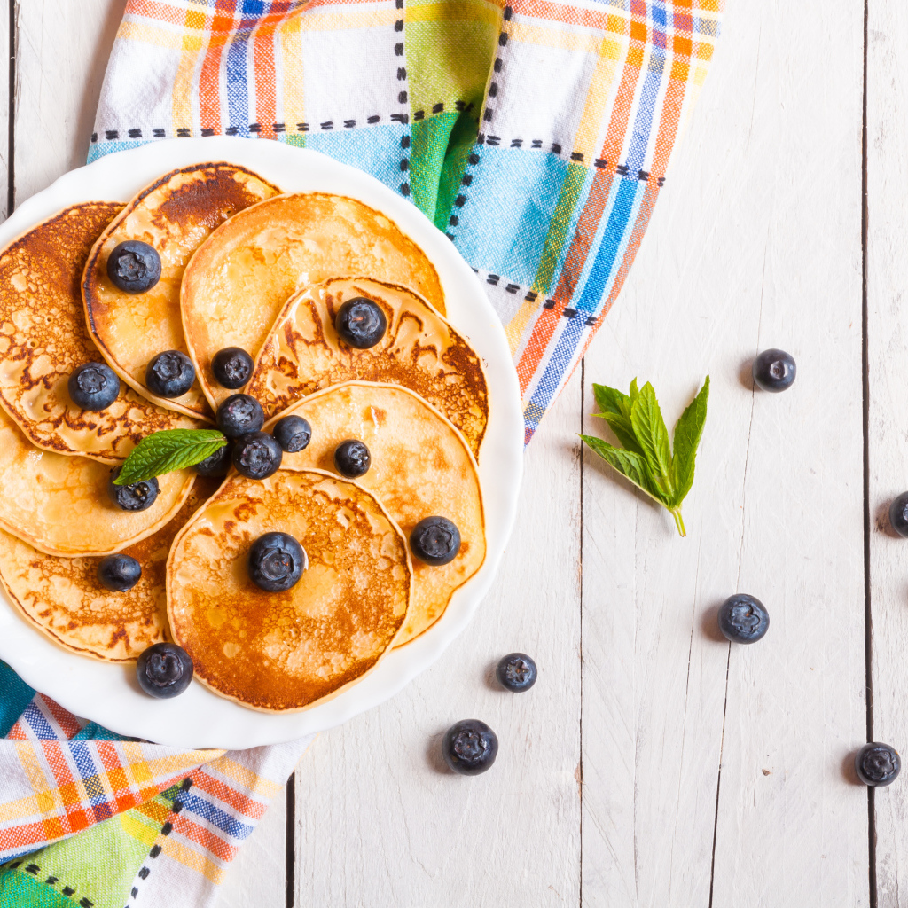 Румяные оладьи на тарелке с ягодами черники