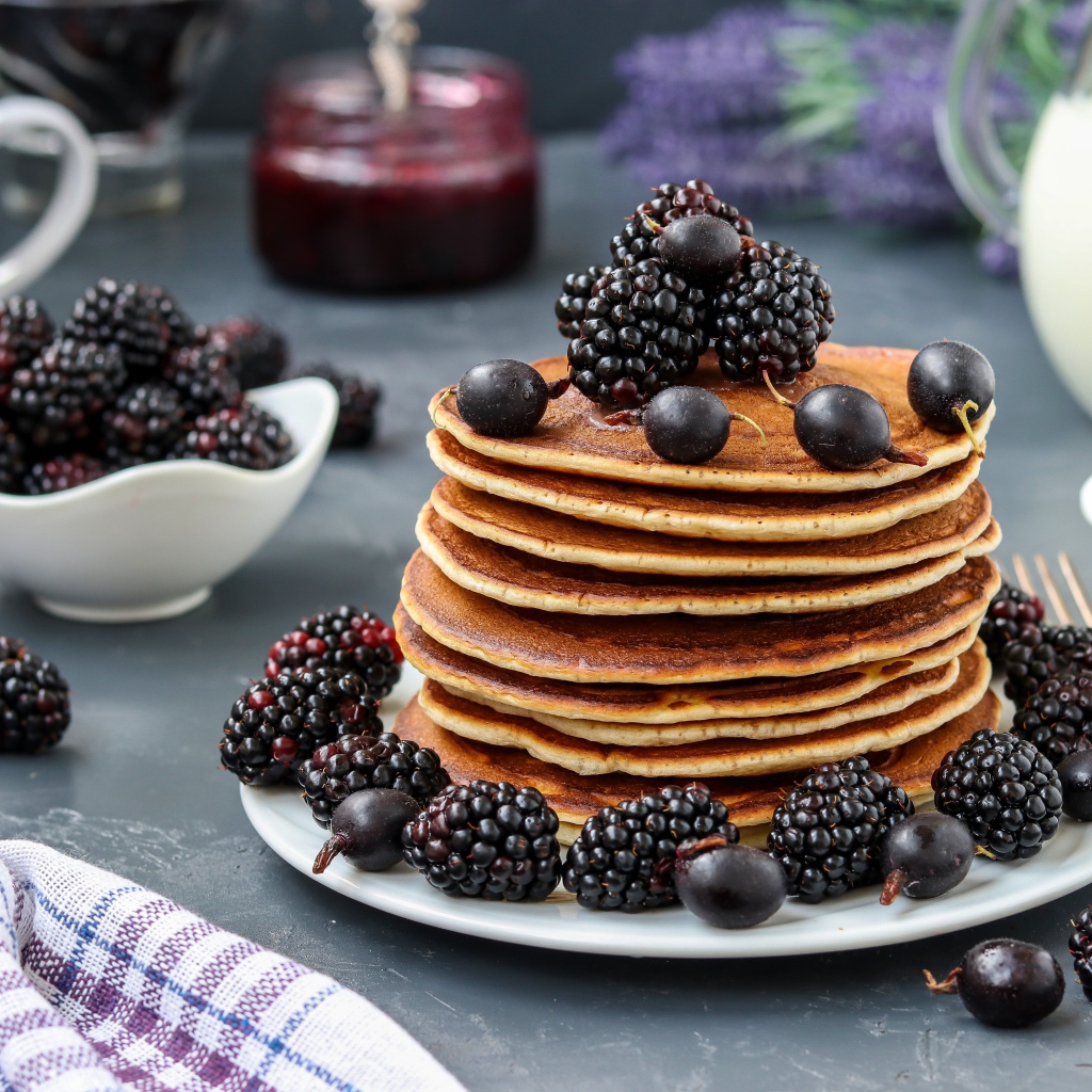 Румяные оладьи на тарелке с ягодами черники и смородины