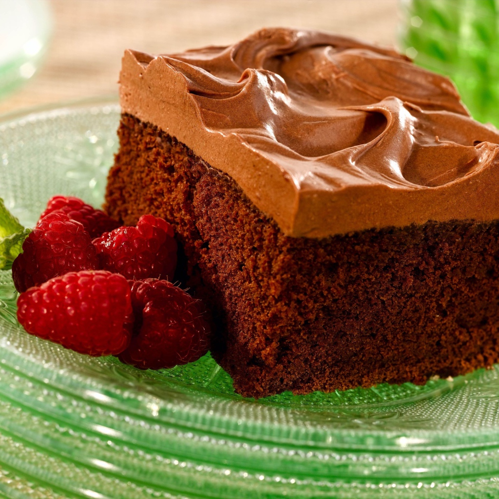 Бисквит с кремом и свежей малиной на тарелке