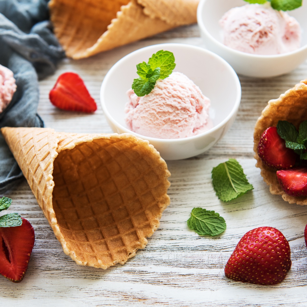 Клубничное мороженое на столе с рожками и клубникой