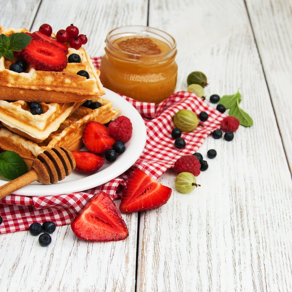 Сладкие вафли на столе с ягодами и медом